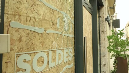 Broken storefront after street riots with SALES text in French
