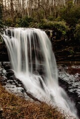 Obraz premium Long exposure shot of a majestic waterfall cascading into a lush grassy field.