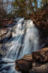 Fototapeta na wymiar Majestic waterfall cascades down a densely forested ravine.