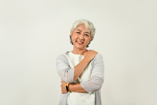 Positive Mature Woman Hugging Herself And Smiling To Camera Isolated On White Background