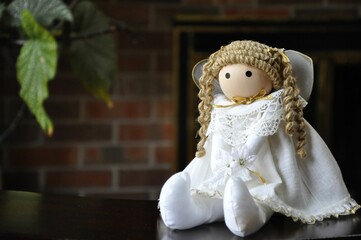 White angel doll with a golden hair on a wooden table
