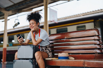 Fototapeta premium Asian teenage girl african american traveling using smartphone moblie while waiting for a train at a station.