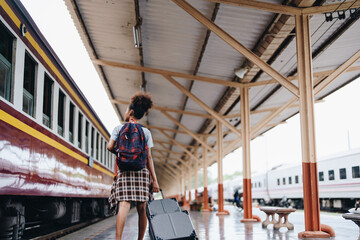 Tourists african american are showing happy expressions while waiting for their journey in the train station.