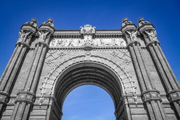 Obraz premium Low angle shot of the historic Arc de Triomphe against a blue sky in Barcelona, Spain