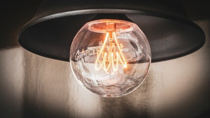 Illuminated light bulb suspended from a wall-mounted lamp holder