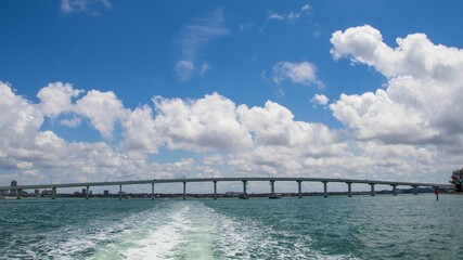 the water under a bridge with clouds above it as seen from a boat