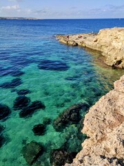 Coastal cliffs surrounded by bluish-turquoise waters.