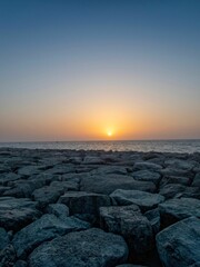 Vertical shot from a rocky beach of a sea during a sunset