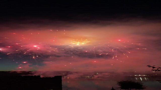 Vertical shot of colorful festive fireworks above the river at night