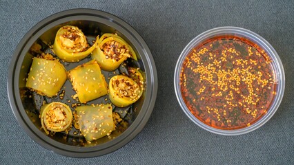 Black bowl filled with Laping rolls and sauce on a kitchen countertop