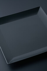 Black square-shaped plates or bowls for food on a black background.