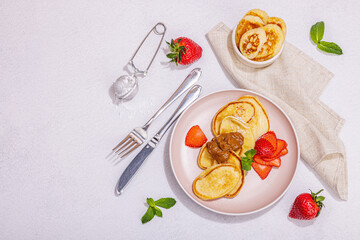 Cottage cheese pancakes, syrniki, curd fritters with strawberry, mint and powdered sugar on plate