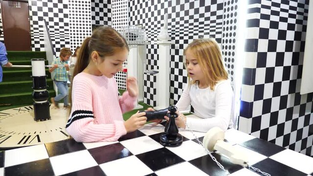 Excited tweenagers trying to find solution of conundrum in lost room designed as chessboard