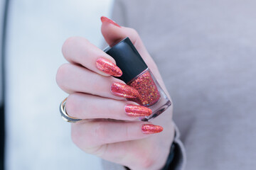 Female beautiful hand with long nails and a bright red orange nail polish