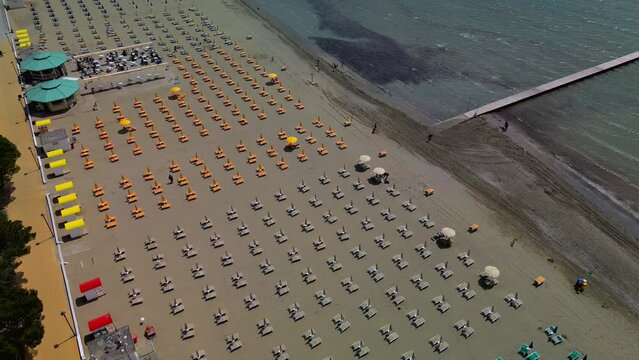 Aerial view of the sandy beach surrounding the city. Equipped beaches with umbrellas and sun loungers for the summer holidays. Journey. embankment. Adriatic Sea. Italy Grado 20.07.2023