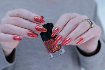 Female beautiful hand with long nails and a bright red orange nail polish