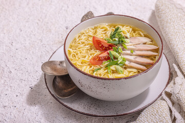 Spicy noodles with beef broth. Hot dish, cutlery, hard light, dark shadow. Stone concrete background
