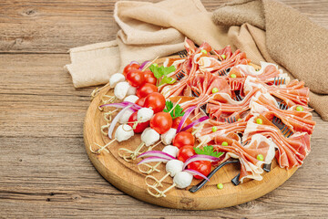 Set of picnic snacks on skewers. Jamon, mozzarella, cherry tomatoes, peas, fresh greens
