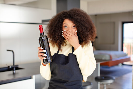 pretty afro black woman covering mouth with a hand and shocked or surprised expression. wine bottle concept