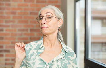 senior pretty woman looking arrogant, successful, positive and proud, pointing to self