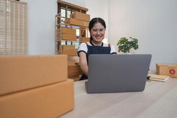 Young business woman working online ecommerce shopping at her shop. Young woman seller prepare parcel box of product for deliver to customer. Online selling, ecommerce