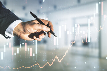 Man hand with pen working with abstract virtual financial graph on blurred office background, financial and trading concept. Multiexposure