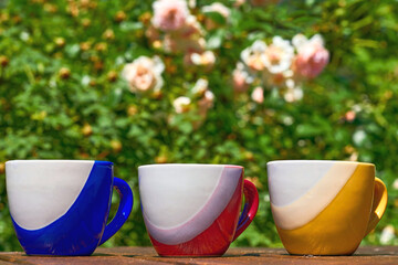 Teatime. tea coffee cups and flowers in greenery on a wood surface