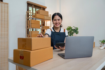 Young business woman working online ecommerce shopping at her shop. Young woman seller prepare parcel box of product for deliver to customer. Online selling, ecommerce