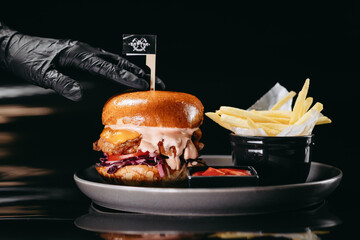 Burger with crispy chicken fillet and fries on a black background