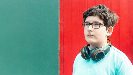 Portrait of eleven years old boy in glasses and wireless headphones, horizontal, copy space