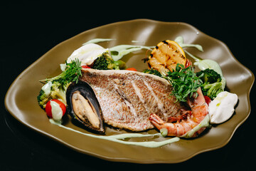Dorado fillet fish dish on a green plate on a black background