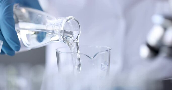 Scientist chemist pouring water from flask into glass 4k movie. Water hardness analysis concept