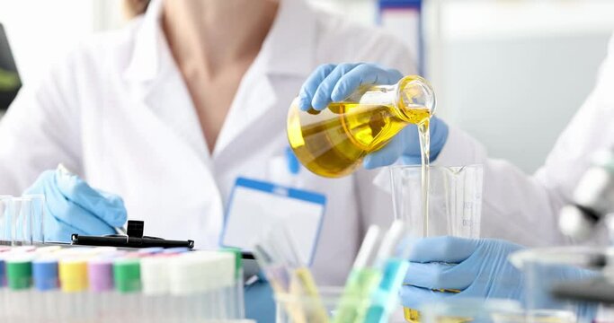 Chemist pouring oil into glass from flask 4k movie. Engine oil quality control concept
