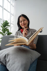 woman sit at sofa hold pencil take notes to paper notebook working studying. Female student businesswoman employee write records to daily planner by hand at home work desk