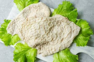 Cleaned and washed raw cattle tripe on cutting board on bright rustic table