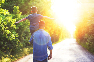 A Happy child on the shoulders of a parent in nature on the way to travel