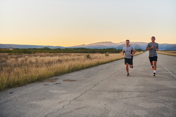 Obraz premium Group of handsome men running together in the early morning glow of the sunrise, embodying the essence of fitness, vitality, and the invigorating joy of embracing nature's tranquility during their