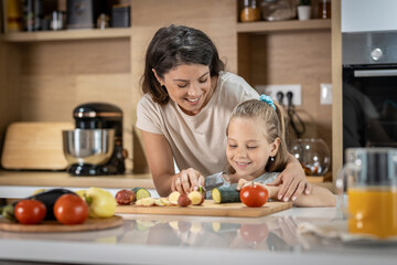 Obraz na płótnie Canvas Happy mother and daughter smiling and prepare delicious vegetables 