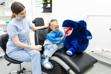 Little child in dentists surgery learning how to brush teeth with giant toothbrush