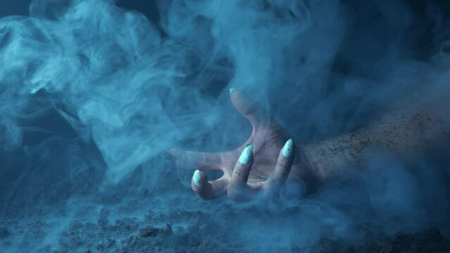 A terrible hand with claws emerges from the fumes of smoke and scratches the graveyard soil.