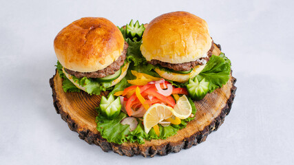 Two beef burgers with vegetables on tray