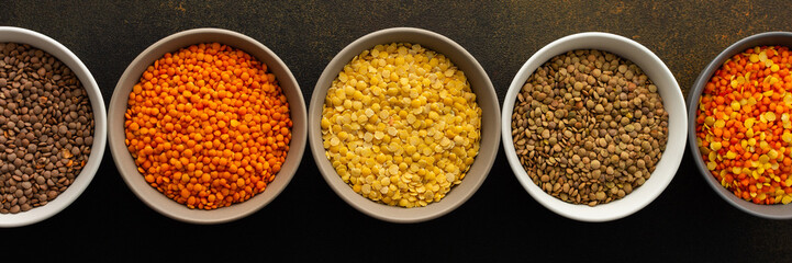 Multicolored lentils in bowls banner, yellow and brown, green and orange lentils, healthy legumes, top view, copy space