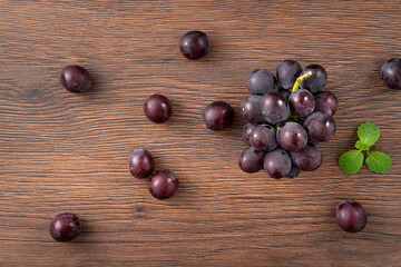 Delicious bunch of grapes fruit spilled over wooden table background.