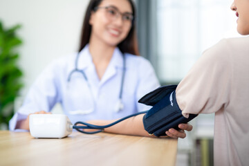 Close up hand of A female doctor wearing armband for measuring blood pressure with digital sphygmomanometer to patient at hospital.