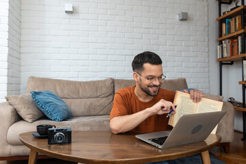 Young smart intelligent student man sitting at home on floor working as freelancer distant foreign...