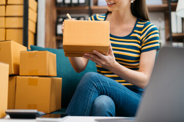 Shipping shopping online ,woman start up small business owner writing address on cardboard box at workplace.small business entrepreneur SME or freelance America woman working with box at home.
