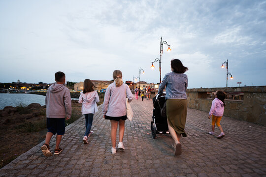 Group of children with mother walking on the promenade in the evening Nessebar, Bulgaria.