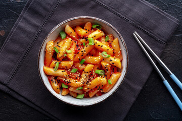 Tteokbokki or topokki, Korean street food, spicy rice cakes in red pepper gochujang sauce, overhead flat lay shot with chopsticks