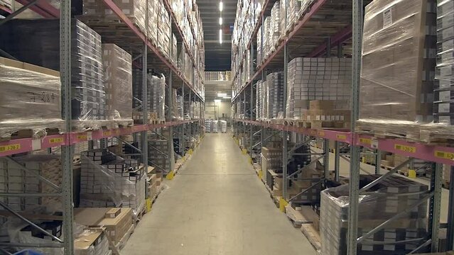 tilt up wide shot of ascending view of warehouse with very high ceilings and shelves full of goods