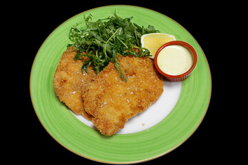 breaded deep fried pork tenderloin known as schnitzel or escalope with sour cream and rocket lettuce